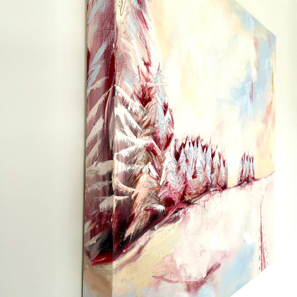 side view of oil painting. Snowscape painting depicting winter landscape hanging on wall in pastel tones of pink blue and white.