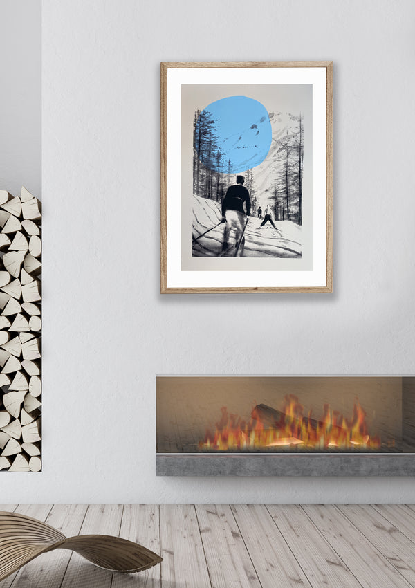 A limited edition screen print of a skier on a snowy mountain, predominantly in black, white, and gray tones with a blue circle emphasizing the sky framed on the wall.
