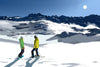 Illustration of a skier and a snowboarder looking out over a snowy mountain range under a bright sun.