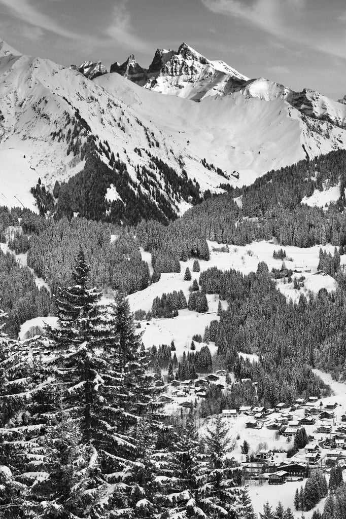  Large mountain photo print. A black and white vertical landscape showing the snow-capped peaks of the Dent du Midi towering above a snow-covered alpine village and frosted pine forests in the French Alps.